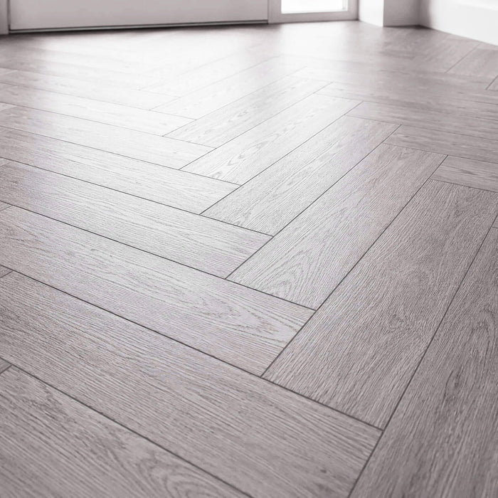 Close-up of Alsace Oak Rigid LVT Herringbone flooring in a home hallway.