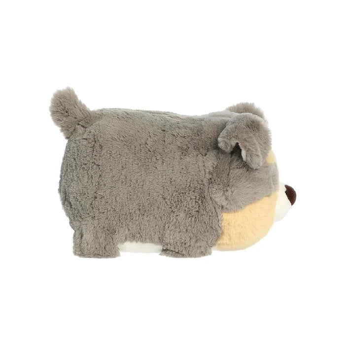 A soft stuffed dog with a white face and brown nose, resting on a colorful blanket, inviting cuddles and play.