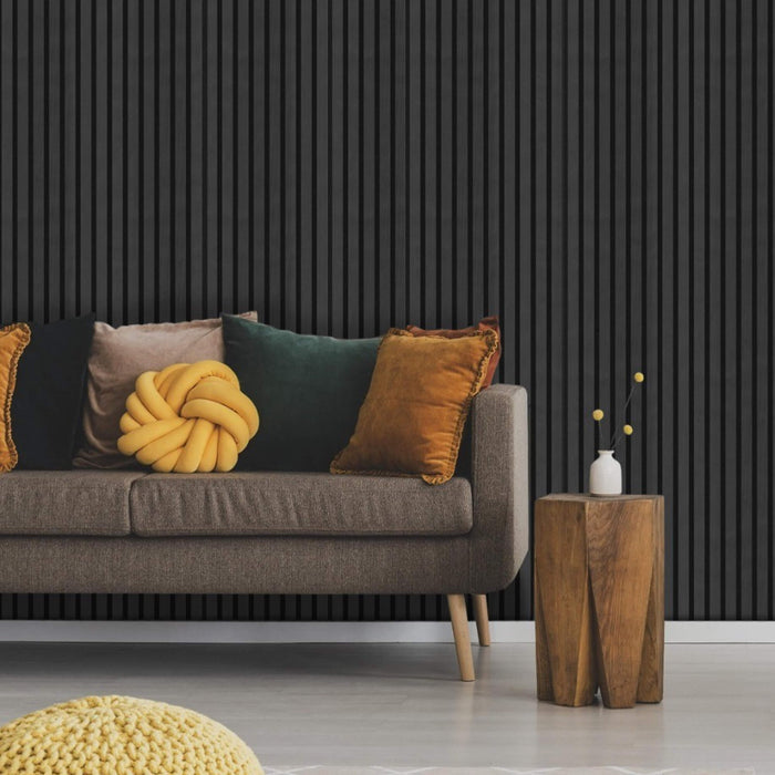 Grey sofa with colorful cushions against a black paneled wall.