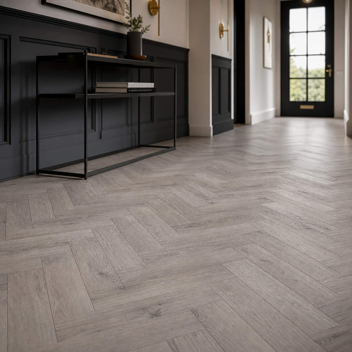 Castle Grey Herringbone laminate flooring in a modern interior hallway with black paneling, a black console table, and a black front door.