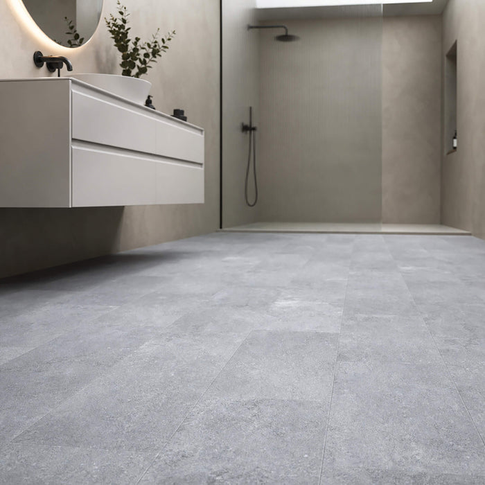 Claros Grey Rigid LVT tile flooring in a bathroom setting with sink and shower area.