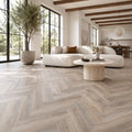 Modern living room with Driftwood Oak Rigid LVT Herringbone flooring, a white sofa, marble coffee table, and large windows.