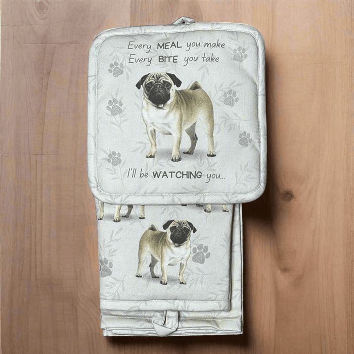 A set of kitchen mitts, pot holder, and a kitchen towel with a Pug dog design on a wooden surface.