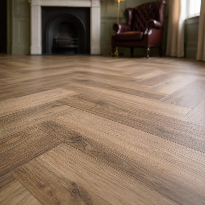 Close-up of a victorian living room with Fumed Oak Rigid LVT herringbone flooring with a fireplace and leather chair.