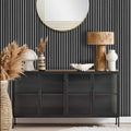 Black sideboard with decorative items against wall with grey slat wall acoustic paneling.