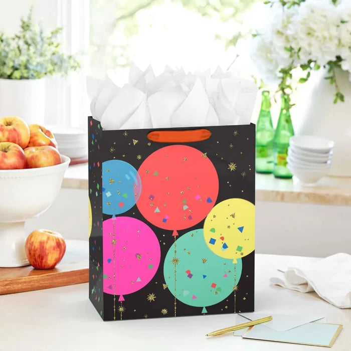 Balloon‑design gift bag on a table next to a card