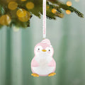 Close-up of hanging pink penguin ornament with Baby's First Christmas 2026 ribbon text