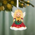 Red and white angel Christmas tree ornament hanging on pine branch