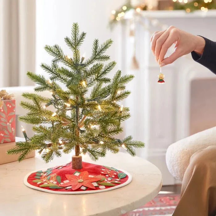 Placing mini porcelain angel ornament on tabletop Christmas tree