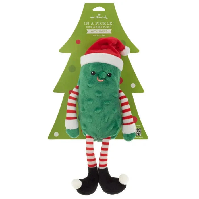 Plush pickle toy with Santa hat and striped scarf on a green tree-shaped card