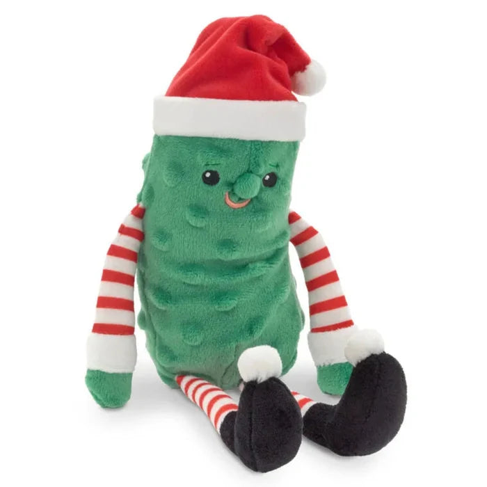 Green plush pickle toy with a red Santa hat and striped legs on a white background