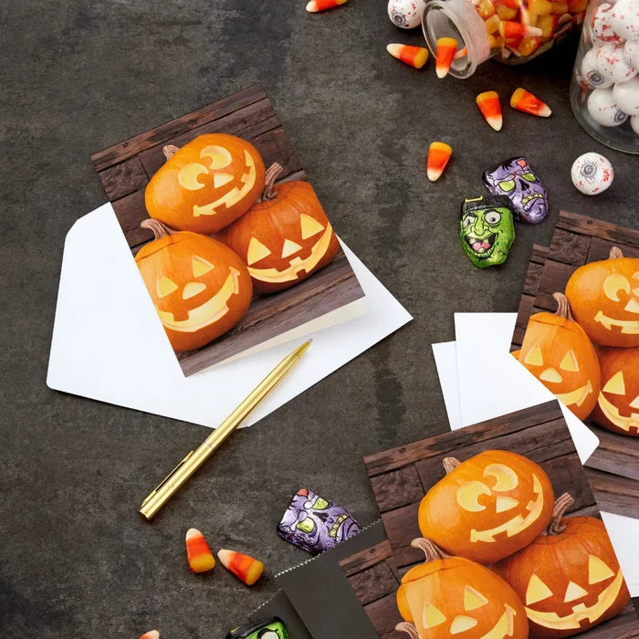 Hallmark Jack-o'-Lantern Trio Halloween card featuring three smiling pumpkins on a rustic wood-plank background.