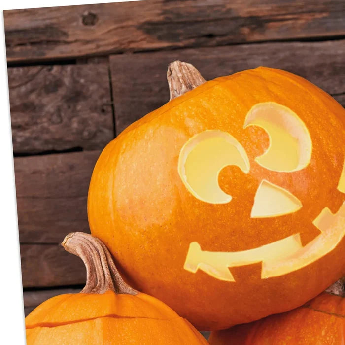 Hallmark Jack-o'-Lantern Trio Halloween card featuring three smiling pumpkins on a rustic wood-plank background.