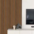 Modern interior with light walnut slatwall  paneling, a television, and decorative sculptures on a white console.