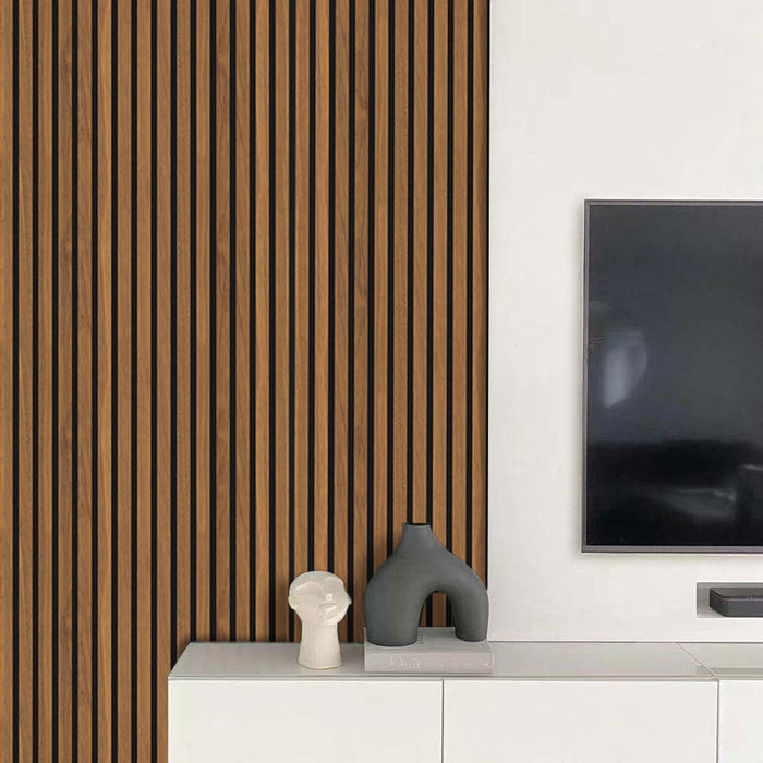 Modern interior with light walnut slatwall  paneling, a television, and decorative sculptures on a white console.