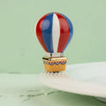 Colorful hot air balloon design on a ceramic plate with a green background