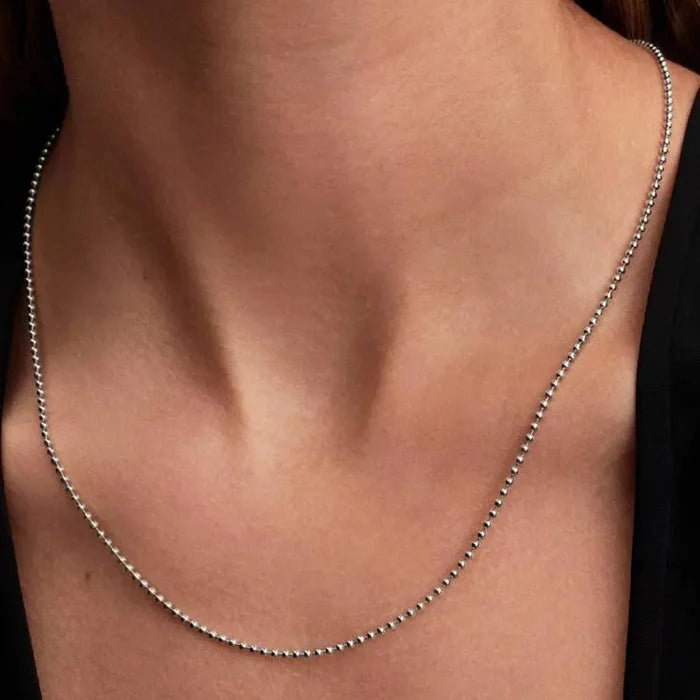 Close-up of a woman’s neck wearing the Pandora Ball Chain Necklace, a modern sterling silver beaded chain.