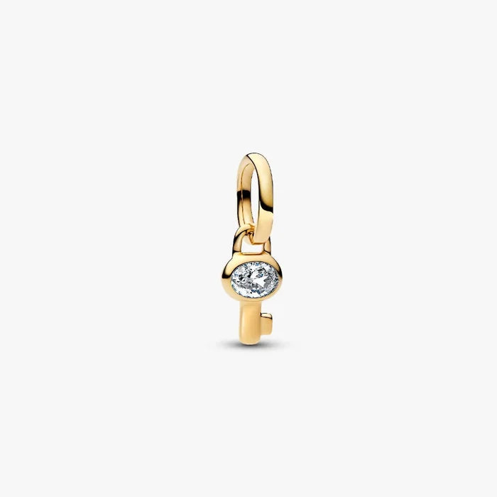 Close‑up of gold‑plated mini key charm featuring clear cubic zirconia