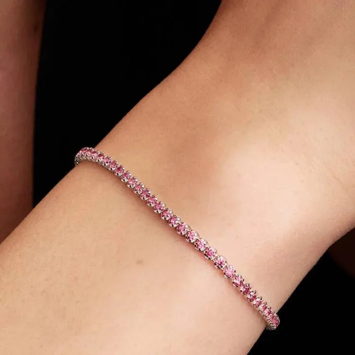 Close-up of a woman’s wrist wearing the Pandora Pink Small Tennis Bracelet, a sterling silver bracelet set with pink cubic zirconia all around.