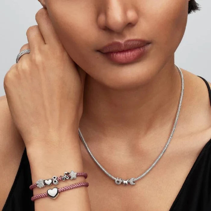 A stylish pink leather bracelet with a braided design and silver clasp.