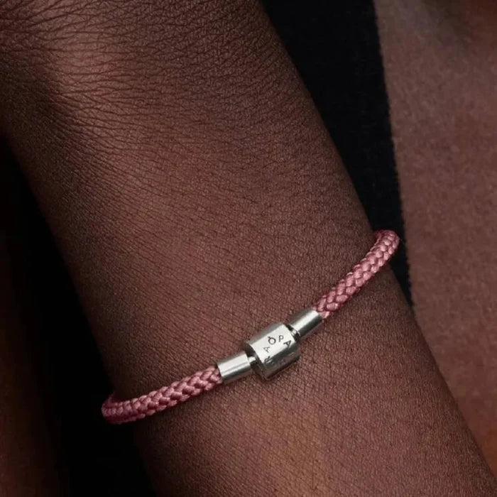 Pink cord charm bracelet with sterling silver clasp displayed on a wrist