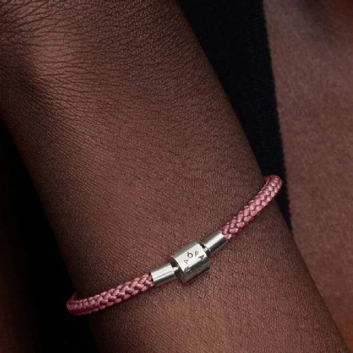 A pink braided leather bracelet complemented by a silver clasp for closure.