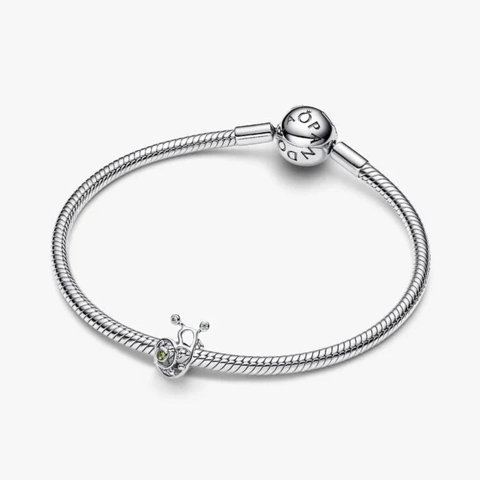 A silver snail charm adorned with green enamel, highlighting its whimsical design and polished surface.