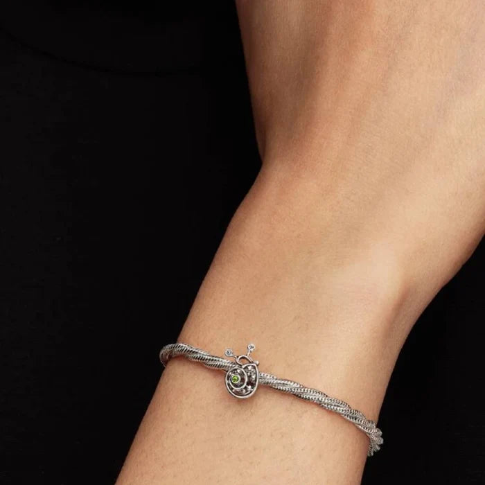 A silver and green enamel snail charm, elegantly designed with smooth curves and a shiny finish.