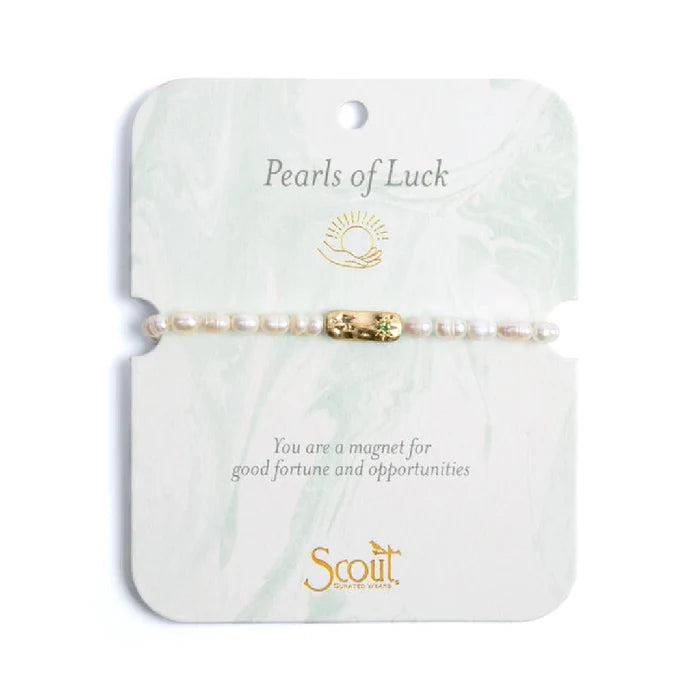 Elegant bracelet featuring pearls, symbolizing luck and charm, displayed on a soft fabric background.
