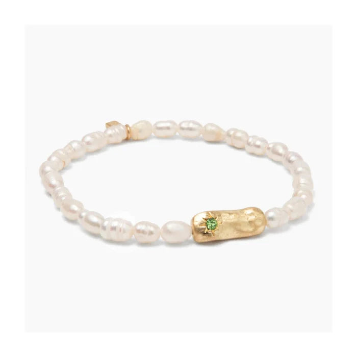 Beautiful pearls strung together in a bracelet, signifying luck, elegantly presented on a light-colored fabric.