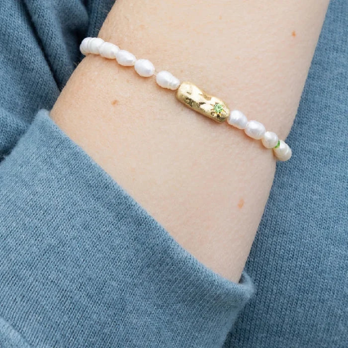 Stylish bracelet made of shimmering pearls, embodying luck, showcased against a subtle textured backdrop.