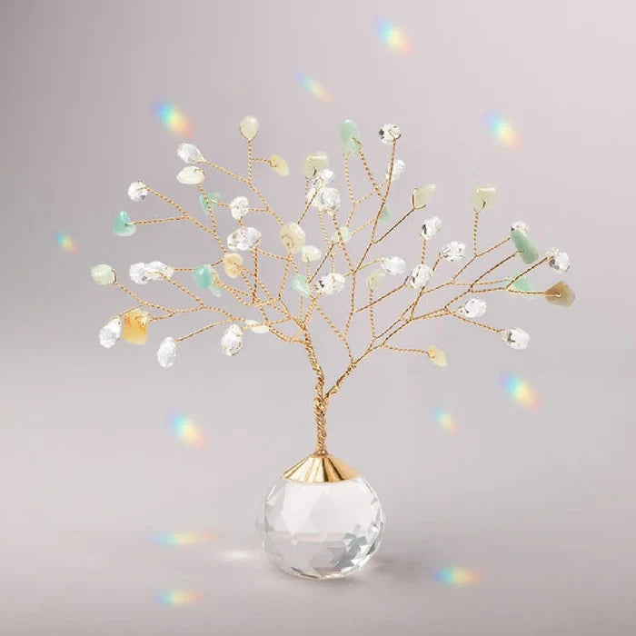 A decorative tree crafted from gold wire and clear and light green beads stands on a faceted crystal ball base.