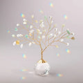 A decorative tree crafted from gold wire and clear and light green beads stands on a faceted crystal ball base.