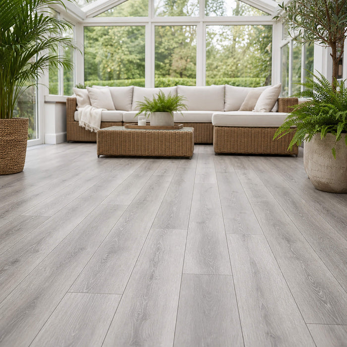 Modern home conservatory with wicker furniture and large windows with Silver Grey Oak Prestige laminate flooring.