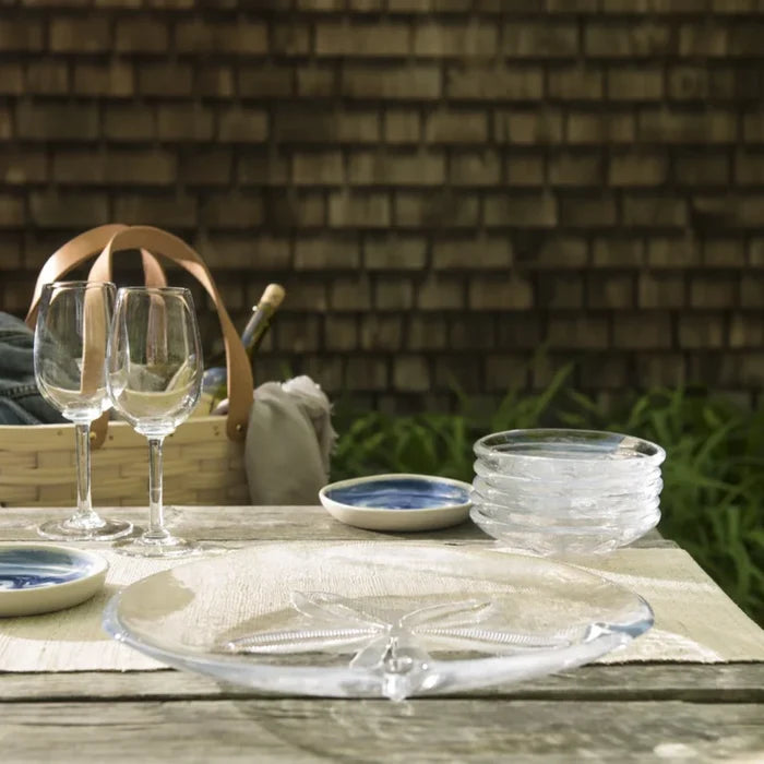 A table set with two glasses, a woven basket, and a plate, creating a cozy dining arrangement.