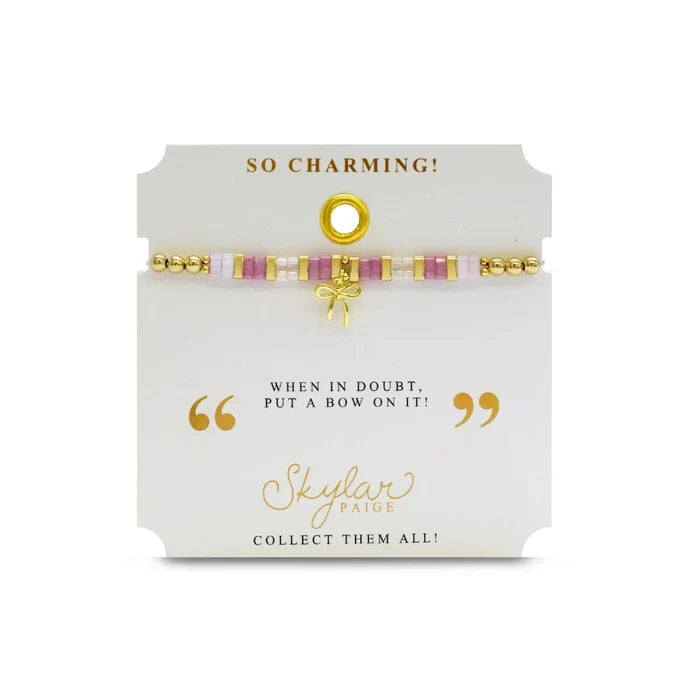 An elegant pink and gold bracelet with a bow detail, combining playful and sophisticated elements in its design.