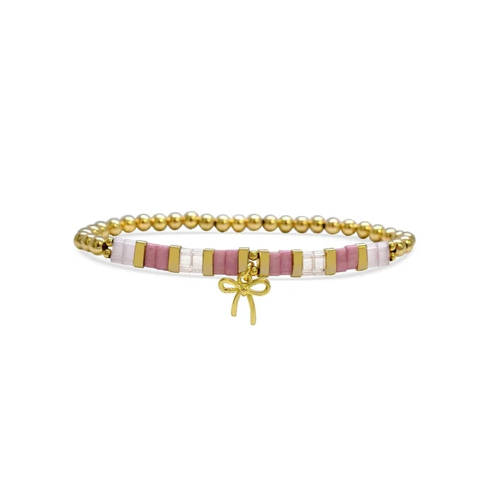 A pink and gold bracelet featuring a decorative bow, showcasing a stylish and elegant design.