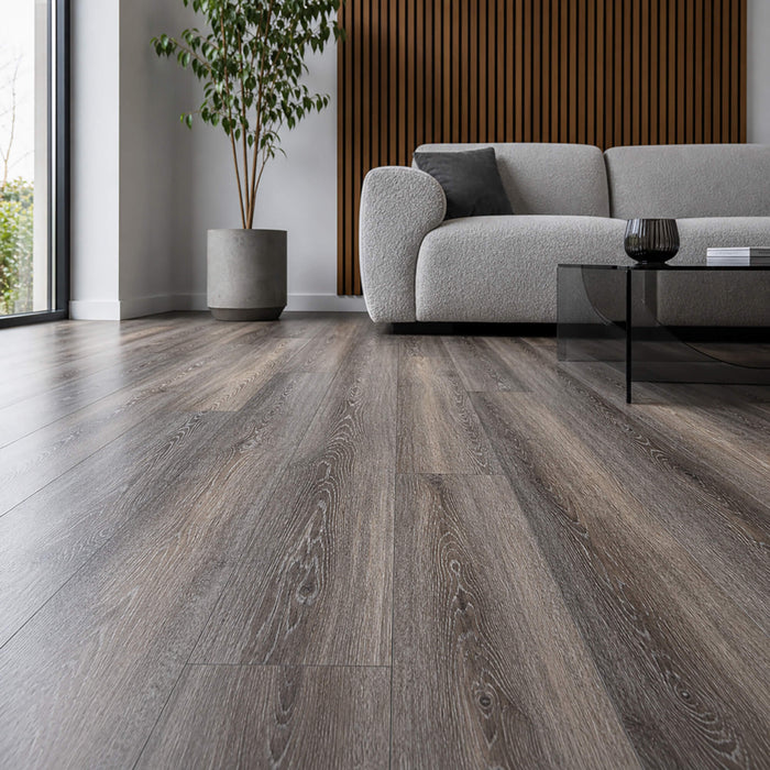 Weathered Oak rigid LVT flooring in a living room setting with a sofa, plant and coffee table.