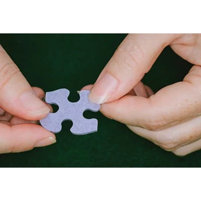A close-up of a hand grasping a puzzle piece, ready to place it in an incomplete puzzle.
